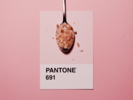 Spoon with coarse pink salt placed over a Pantone 691 color swatch on a pink background