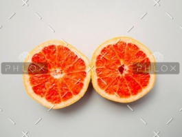 Two halves of a grapefruit placed side by side on a neutral background