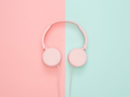 Pink headphones placed on a split pastel pink and teal background