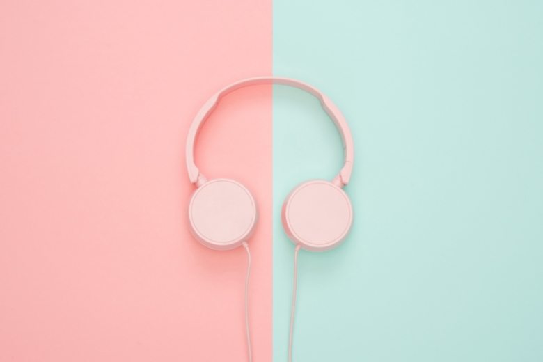 Pink headphones placed on a split pastel pink and teal background