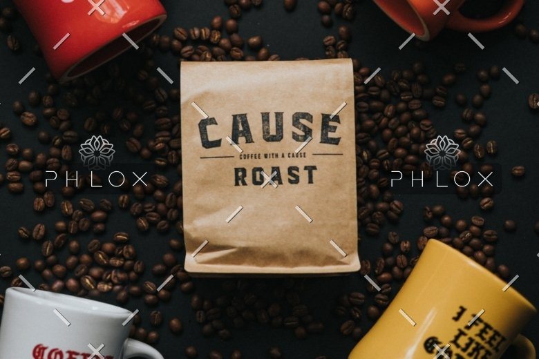 Cause Roast coffee bag surrounded by coffee beans and colorful mugs on dark surface