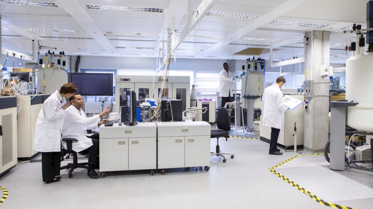 Pharmaceutical laboratory with researchers in white lab coats working on peptide synthesis and analytical methods