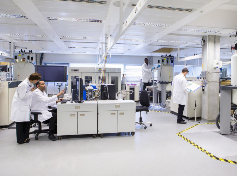 Pharmaceutical laboratory with researchers in white lab coats working on peptide synthesis and analytical methods