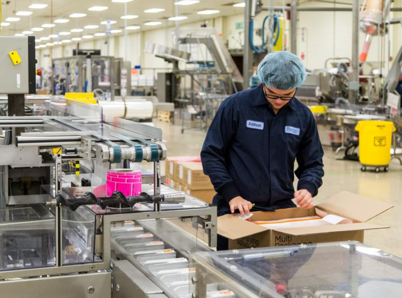 Factory worker packaging products on a production line in a pharmaceutical manufacturing facility