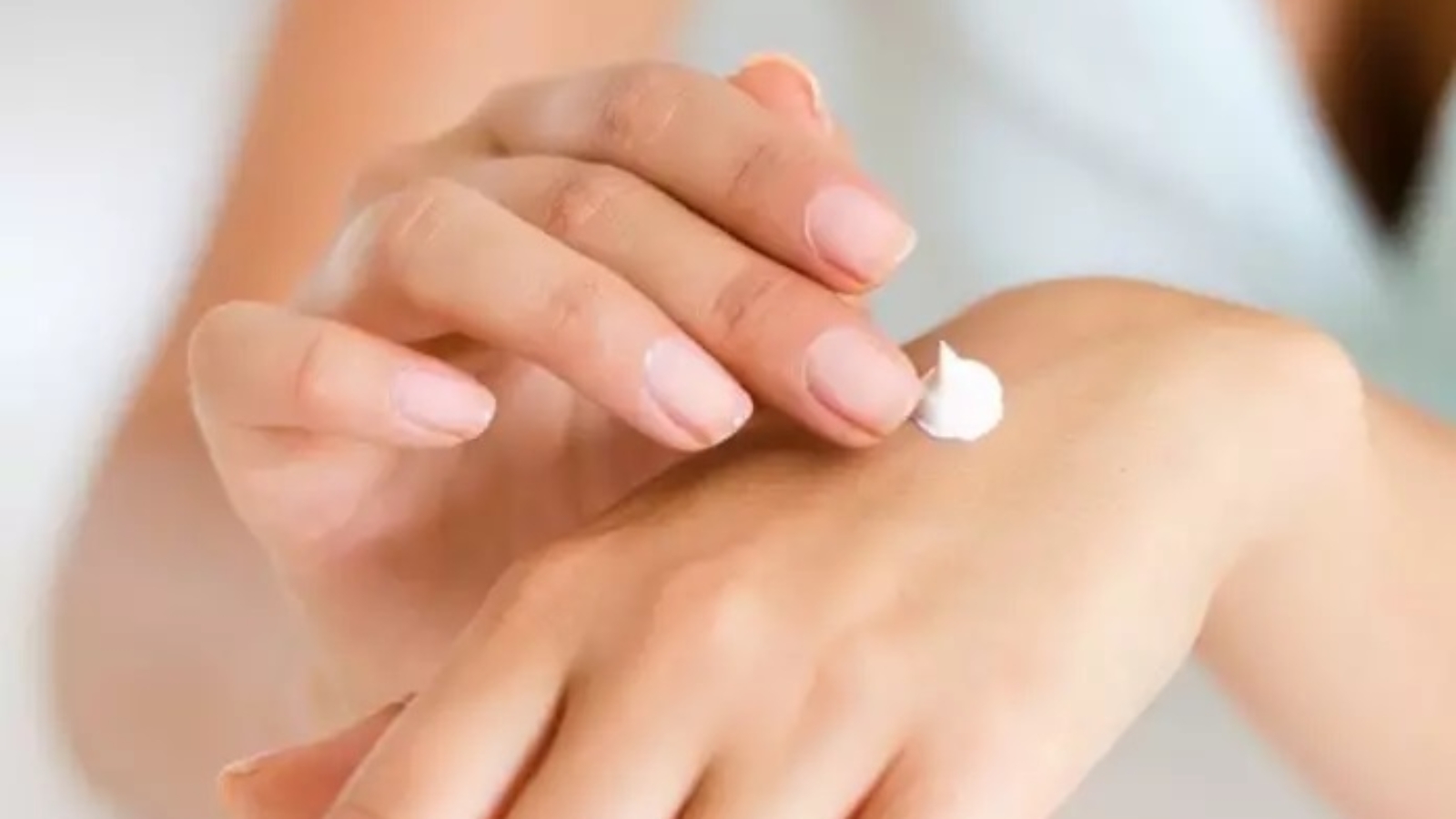 Person applying cream to the back of their hand with focus on smooth skin care