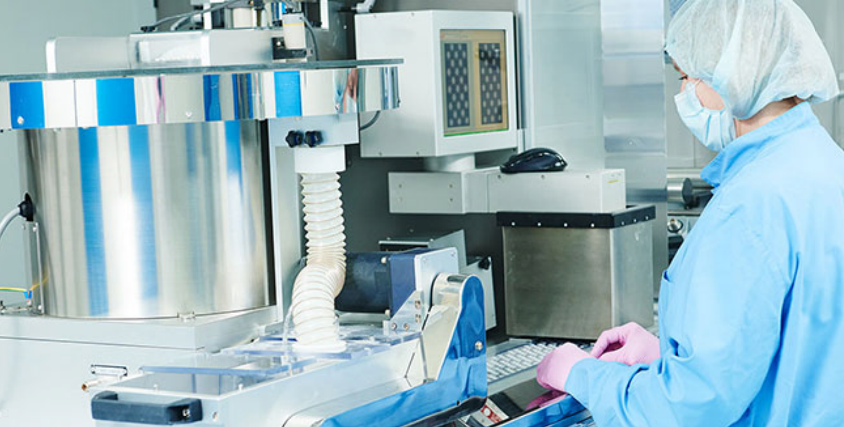 Laboratory technician in protective gear operating automated peptide synthesis equipment in a pharmaceutical manufacturing facility
